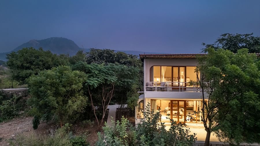 Exterior of a modern two-story villa surrounded by trees and plants.