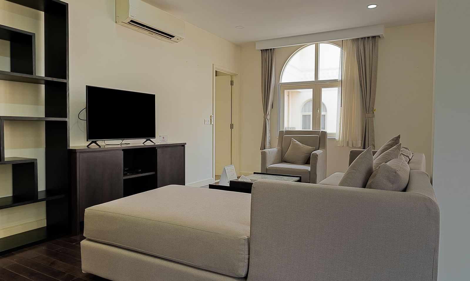 A living room with a white sofa, a TV, and a large window | Four-bedroom Suite | Central Mansions, Phnom Penh