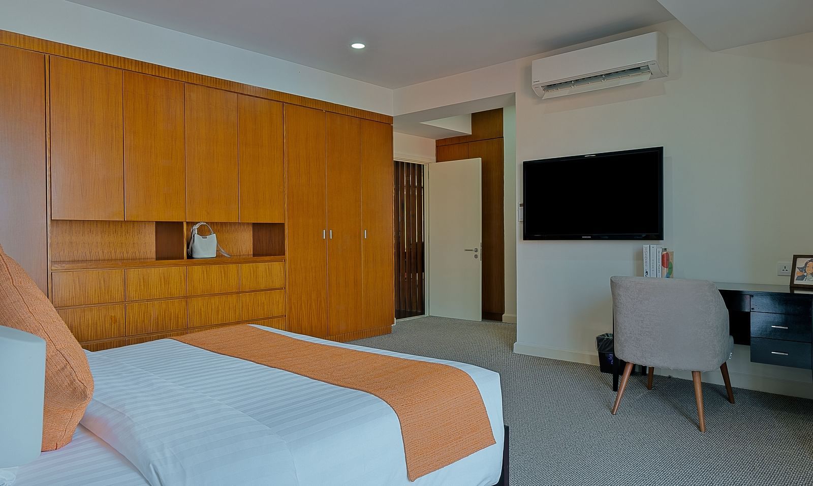A modern room with a large bed, a wooden headboard, and a flat-screen TV | Penthouse | Central Mansions, Phnom Penh