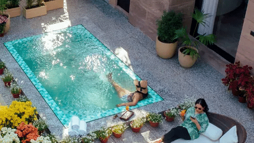 Outdoor hot tub surrounded by plants and seating, placed on a private stone patio with flower pots at Karma Chalets.