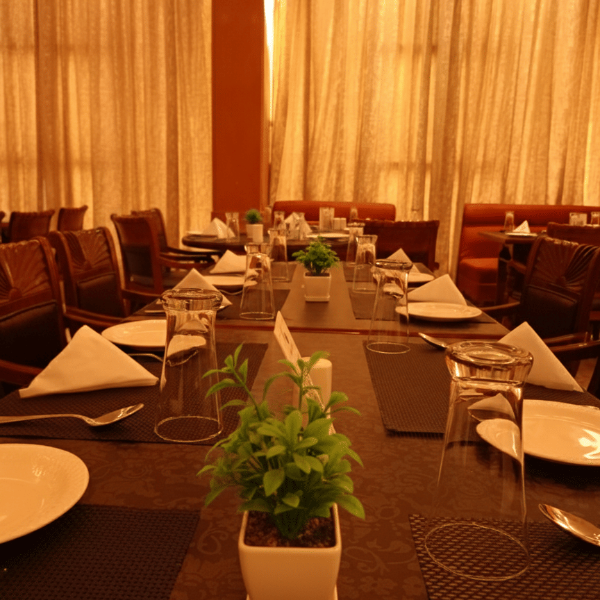 Table setup at Hotel Gold, Panipat with plates, glasses, cutlery, and decor arranged for dining.