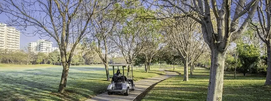 A golf cart on a tree-lined path with two people at Karma Chalets.