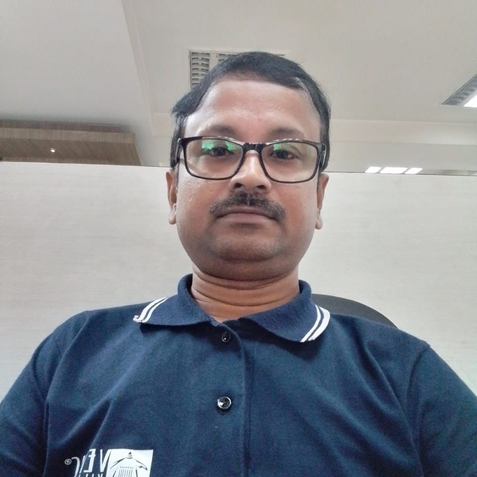 A man wearing glasses and a dark blue shirt looks at the camera