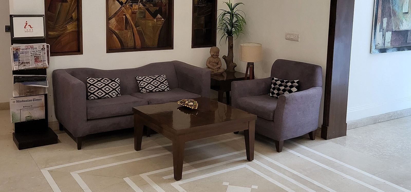 An image of a reception lobby featuring sofa set, centre table, some plants, and photo frames hanged on the wall at Inde Hotel Signature Tower, Gurgaon