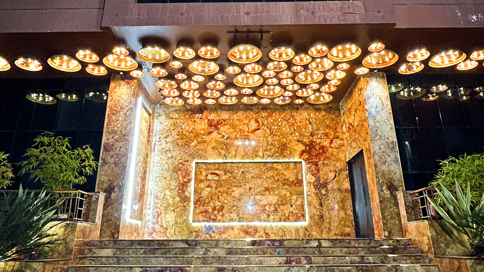 Night view of banquet hall entrance with marble steps and decorative lights at Infiniti Hotel, Indore.