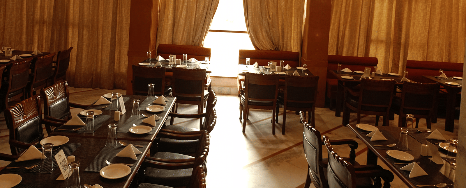 Restaurant at Hotel Gold, Panipat with arranged dining tables, chairs, and hanging lights.