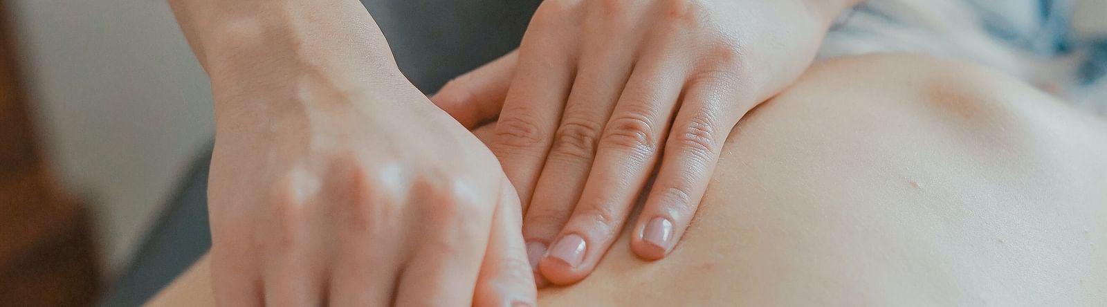 two hands massaging the back of a person at a spa