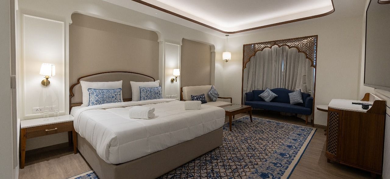 Corner view shot of the Mandakini Room featuring a plush double bed along with a long patterned carpet on the floor at Bhagirathi by RDB Atishay.