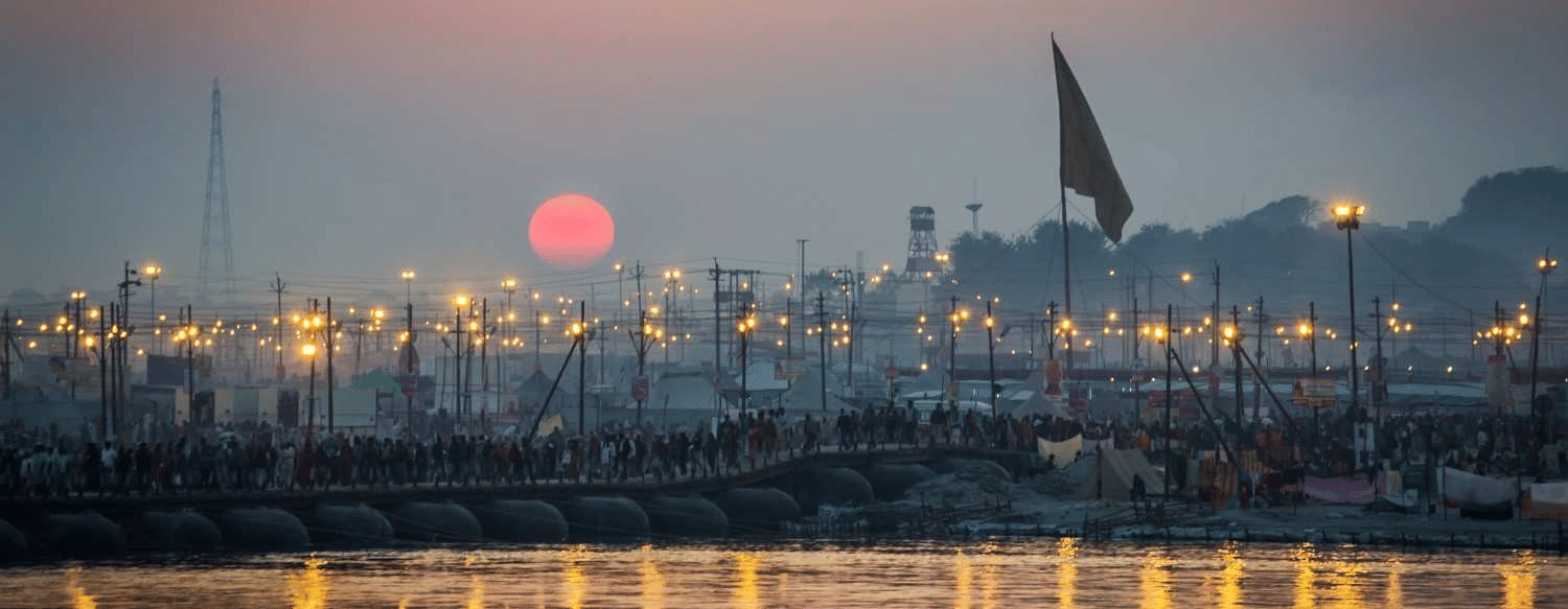 Sunset over Prayagraj river with boats and city lights, captured from the vicinity of the city