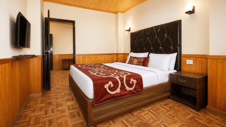 Imperial Suite at Orsino Khangri Karpo Retreat & Spa, Lachung featuring a bed, a bedside table and a flat TV screen mounted on the wall.