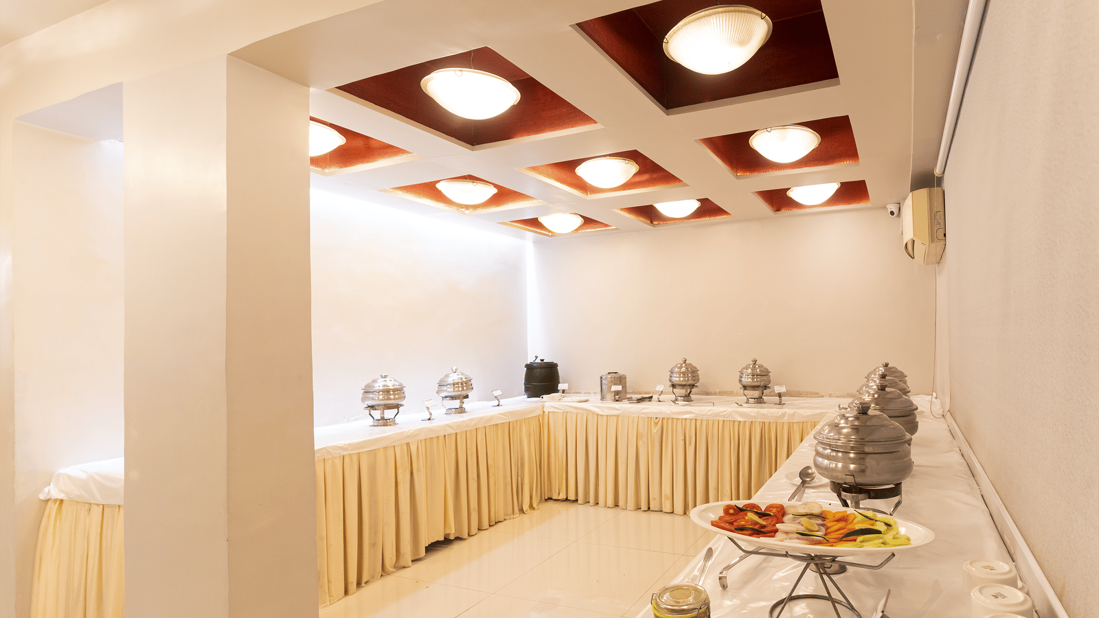 Bright buffet area with marble floor, ceiling lights, and food counter at Infiniti Hotel, Indore.