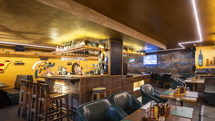 A restaurant interior with high tables, chairs and wall murals in a rustic wooden setting at Infiniti Hotel, Indore.