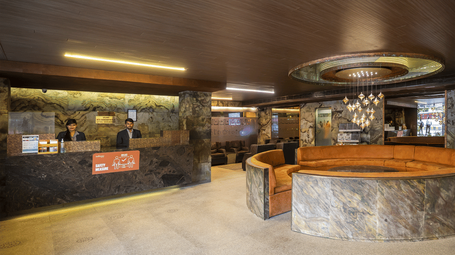 Spacious lobby with marble flooring, a rounded front desk, and ambient ceiling lighting at Infiniti Hotel, Indore.