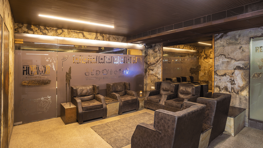 Indoor lounge area with brown cushioned seats, soft lighting, and walls decorated with travel-themed graphics at Infiniti Hotel, Indore.