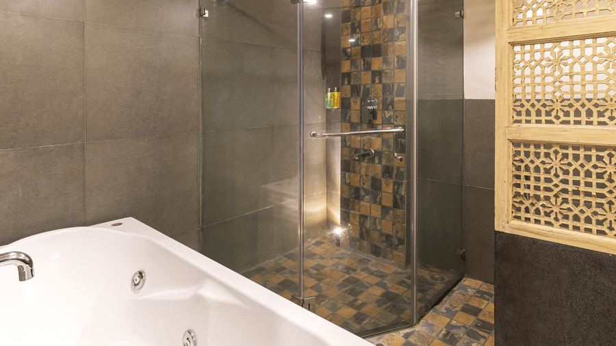 A bathroom with bathtub, tiled walls and decorative panel at Infiniti Hotel, Indore.