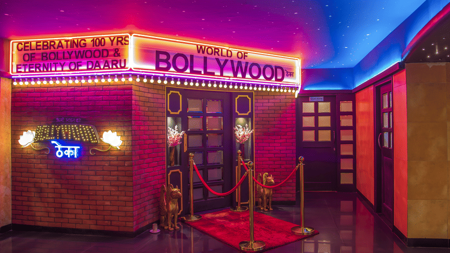 An entrance with a red carpet, ropes, neon lights and a glowing signboard reading 'BOLLYWOOD' at Infiniti Hotel, Indore.