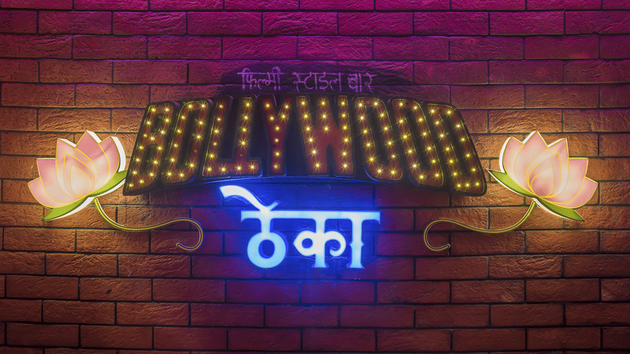 A sign reading 'Bollywood ????' with two lit flowers on a brick wall at Infiniti Hotel, Indore.