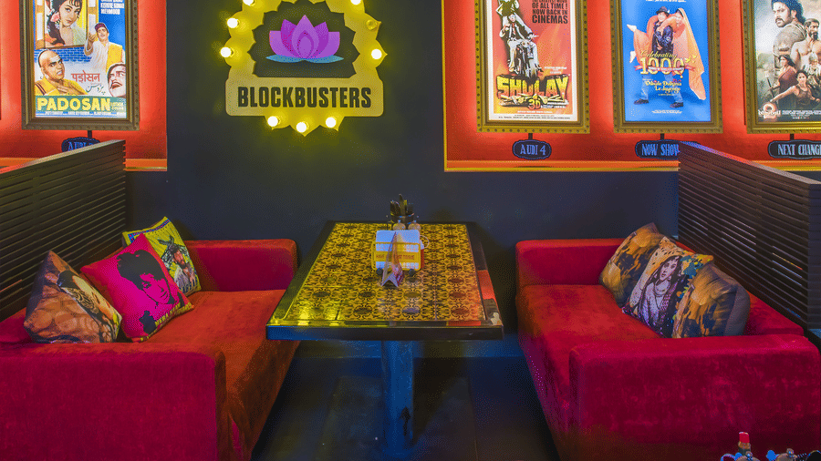 A dining table with patterned top, red sofas and framed Bollywood posters at Infiniti Hotel, Indore.