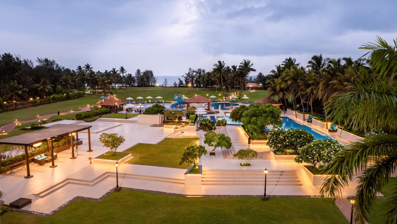 Elevated dusk view of manicured gardens and illuminated pathways at Kenilworth Resort & Spa, Goa.