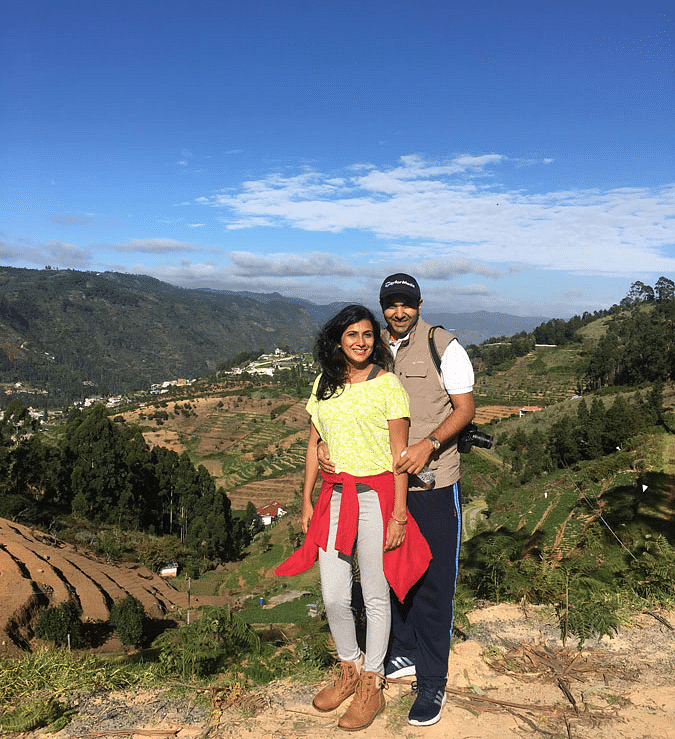 A Couple posing on a scenic hilltop with a clear blue sky