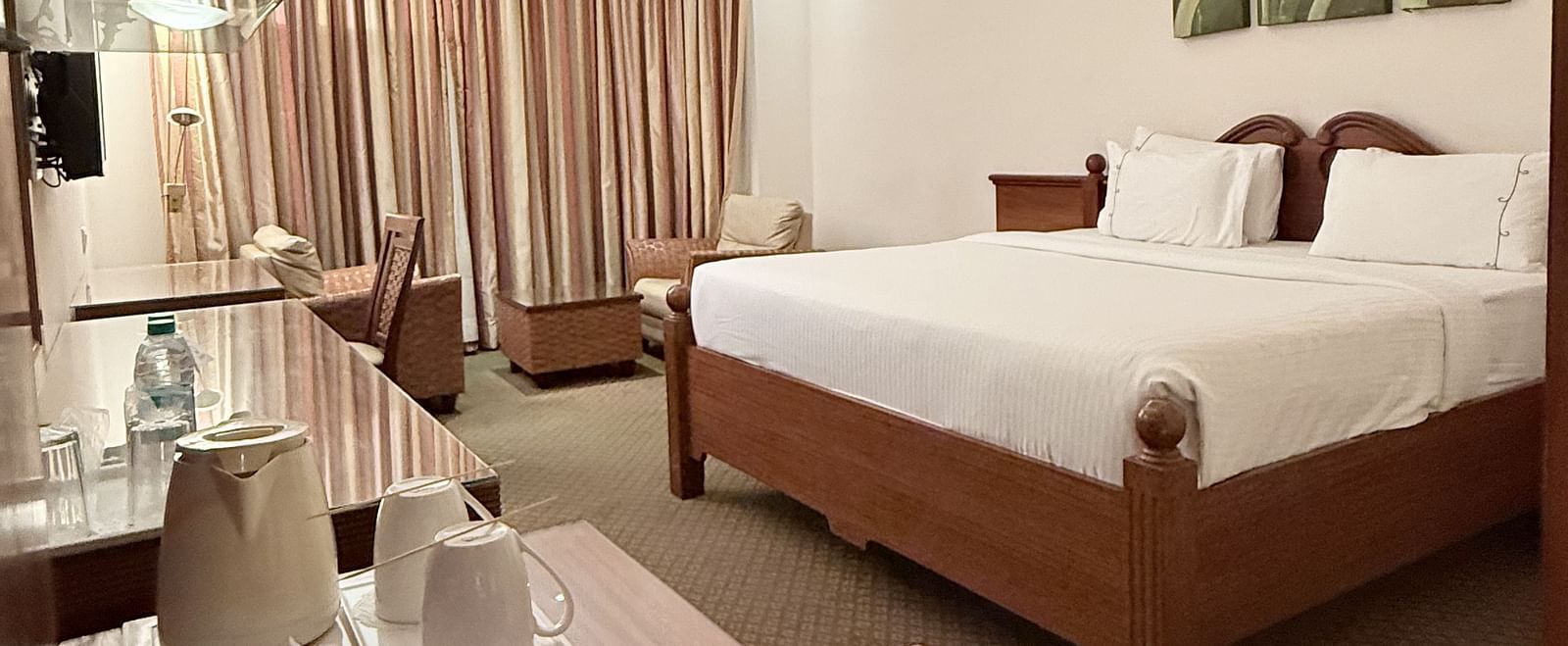 A spacious room with a large bed and a side table holding a tray of essentials | Cenneys Gateway