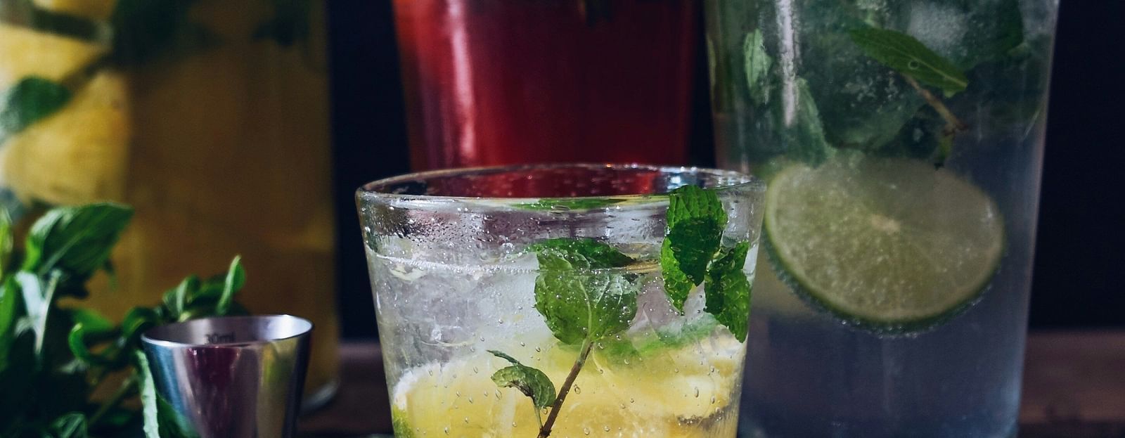 A variety of refreshing mocktails with lime, mint, and fruit infusions in clear glasses, placed on a rustic wooden surface.