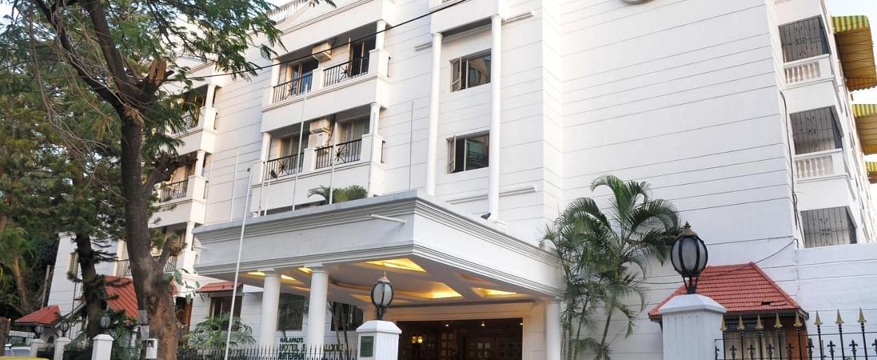 Nalapad Hotel Bangalore International, a white building with a covered entrance, landscaping, and parking.