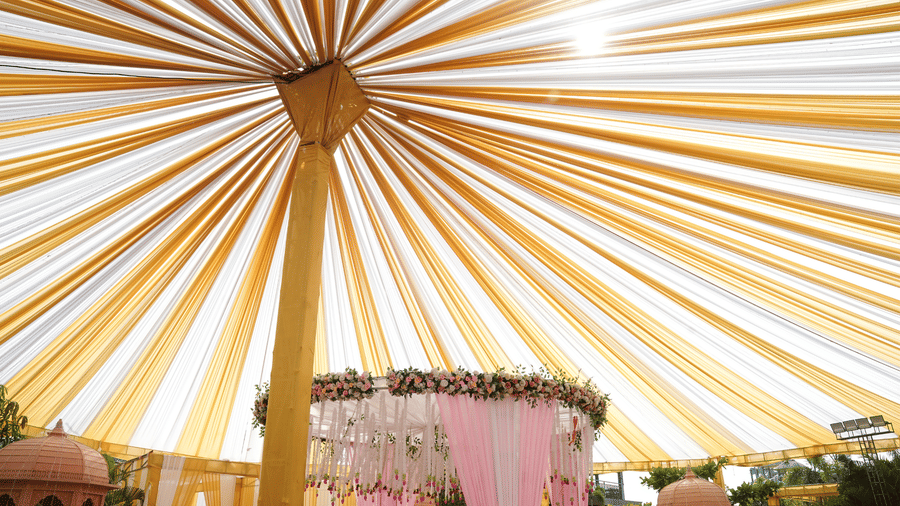 Elegant outdoor wedding canopy with gold fabric draping and a floral chandelier - DAN Resorts & Weddings, Palghar