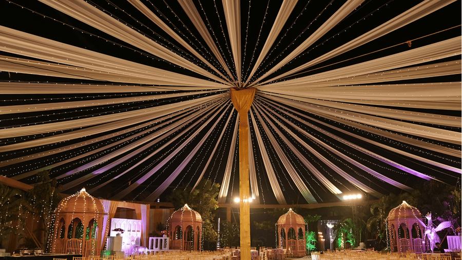 Grand outdoor event space with radial fabric drapes and warm lighting for night celebrations - DAN Resorts & Weddings, Palghar