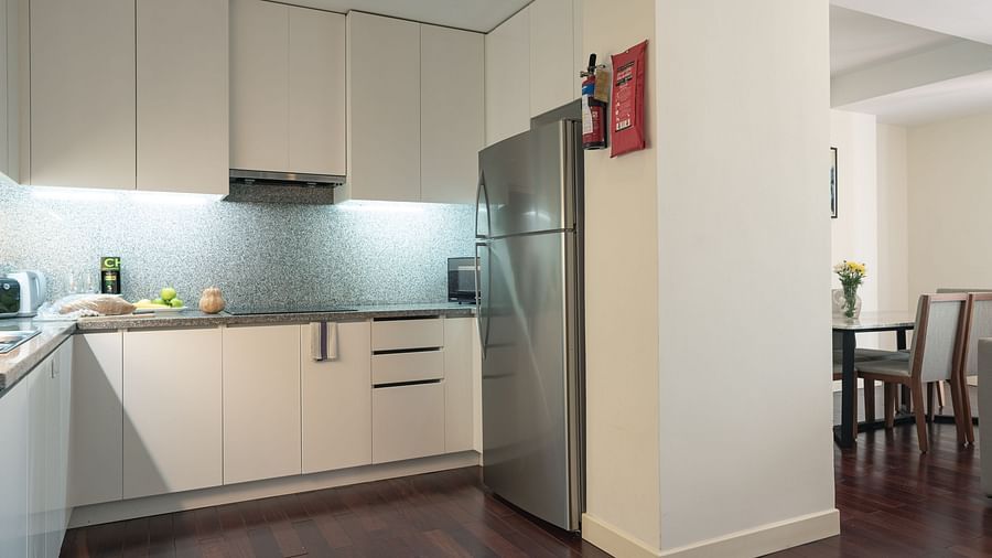 A kitchen with light-coloured cabinets, a refrigerator, and a dining area | Three-bedroom Suite | Central Mansions, Phnom Penh