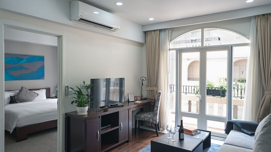 A living room with a grey sofa, a coffee table, and a television | Two-bedroom Suite | Central Mansions, Phnom Penh