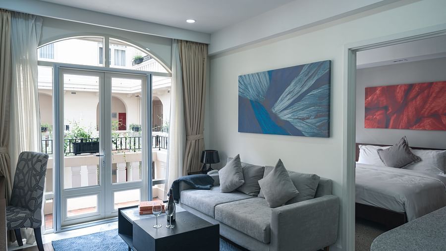 A living room area with a grey sofa, a coffee table, and a painting on the wall | Two-bedroom Suite | Central Mansions, Phnom Penh