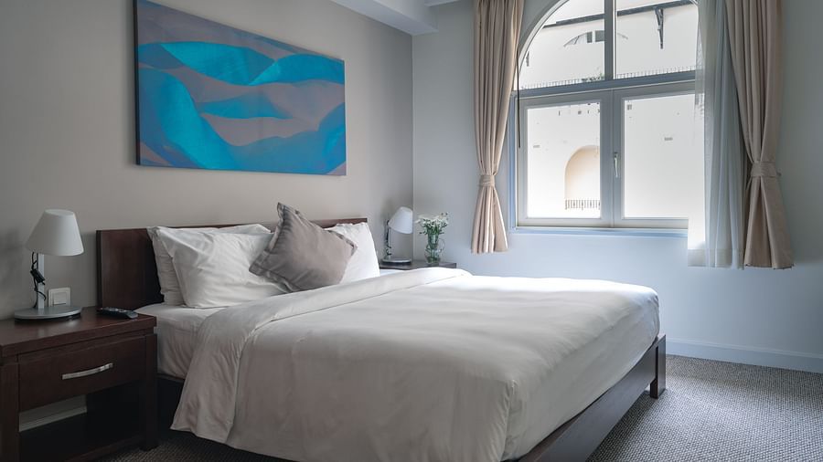 A bedroom with a large bed, a nightstand, and a painting on the wall | Two-bedroom Suite | Central Mansions, Phnom Penh
