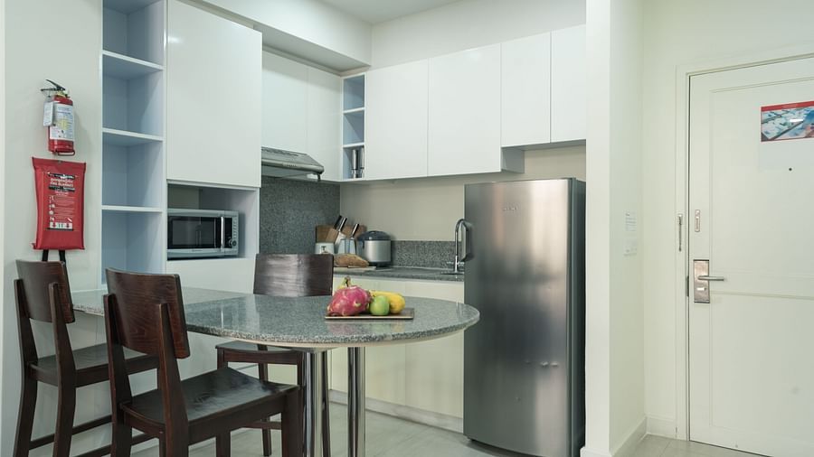 A kitchen with dark wood chairs, a table, a stainless steel refrigerator, and white cabinets | Two-bedroom Suite | Central Mansions, Phnom Penh