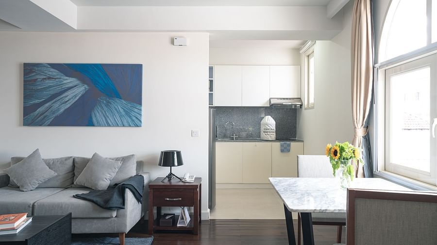 A living room with a sofa, a coffee table, and a small dining table with chairs | One-bedroom Suite | Central Mansions, Phnom Penh