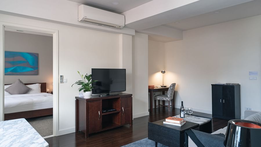 A bedroom with a bed, a television, and a chair | One-bedroom Suite | Central Mansions, Phnom Penh