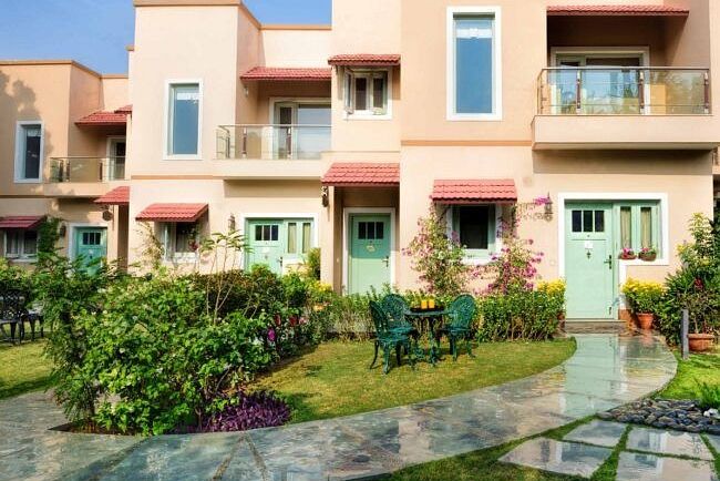 View of pink and peach coloured residential buildings with gardens at Karma Chalets.