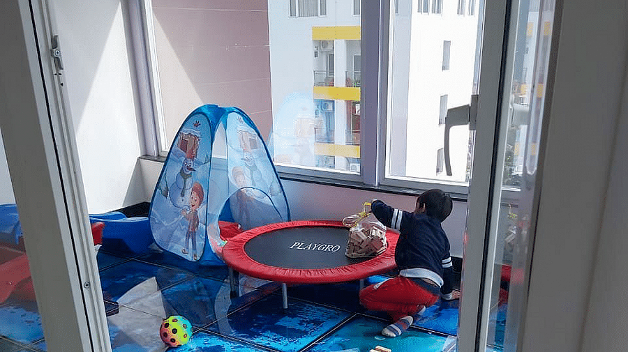 A toddler playing inside the Kids' Play Area with a small trampoline besides him at Regenta Inn DLS.