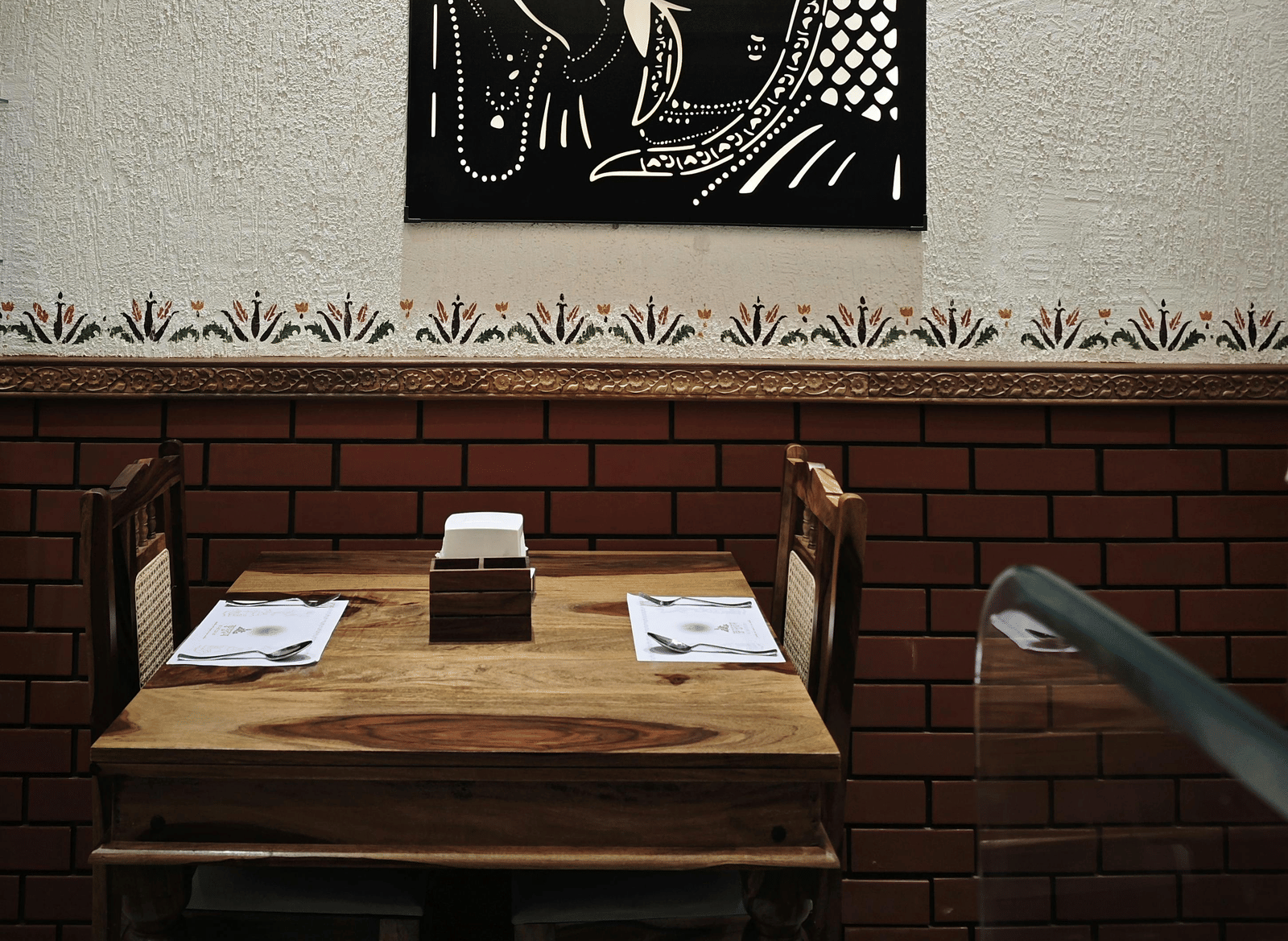 Close-up of a framed artwork hanging above a wooden dining area.