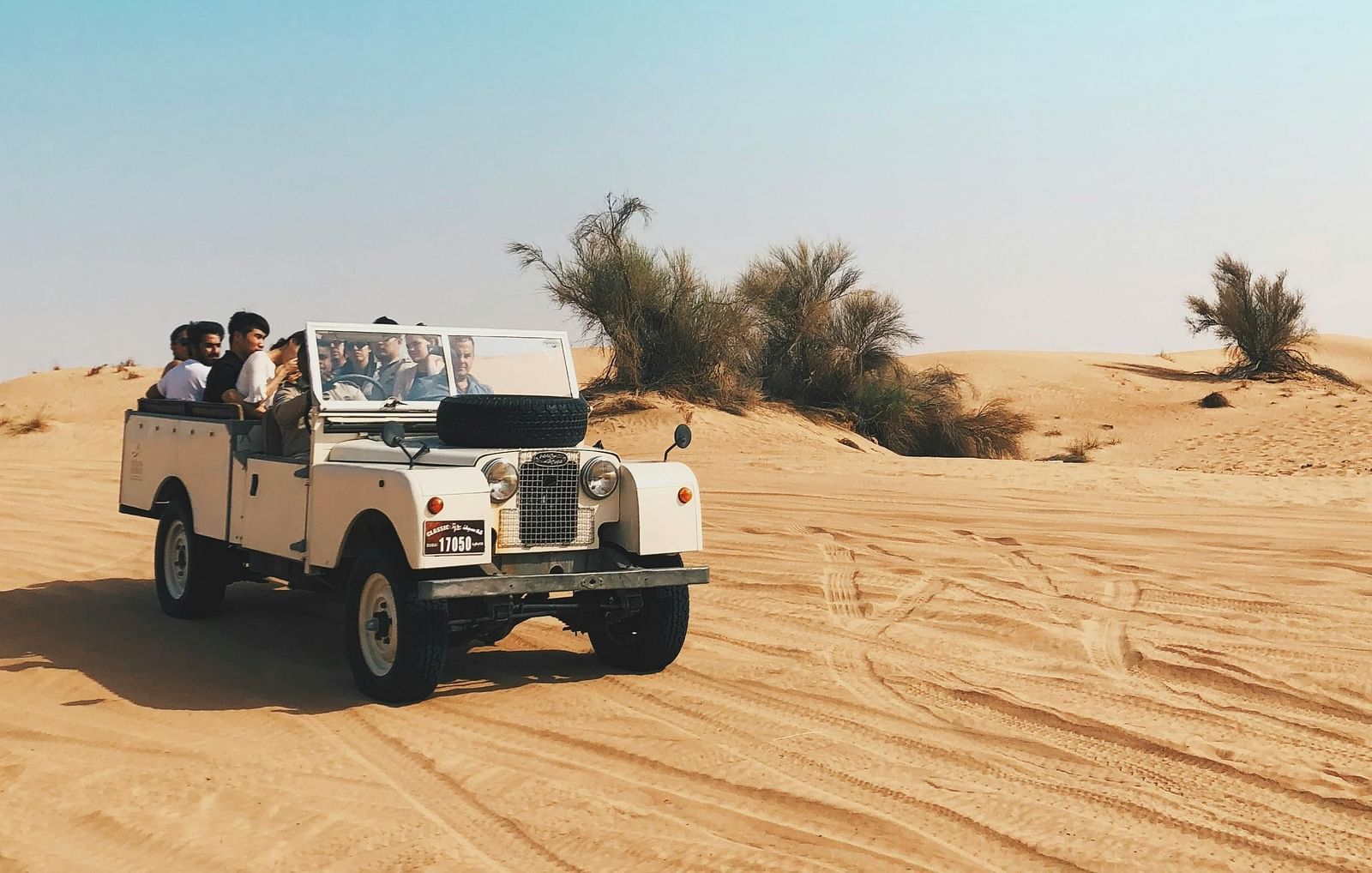 A jeep driving through a sandy desert landscape.