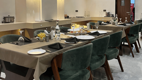 Seating arrangement at Aromas the best restaurant in Jamnagar at VITS, featuring cutlery and napkins placed on the dining table under warm lighting