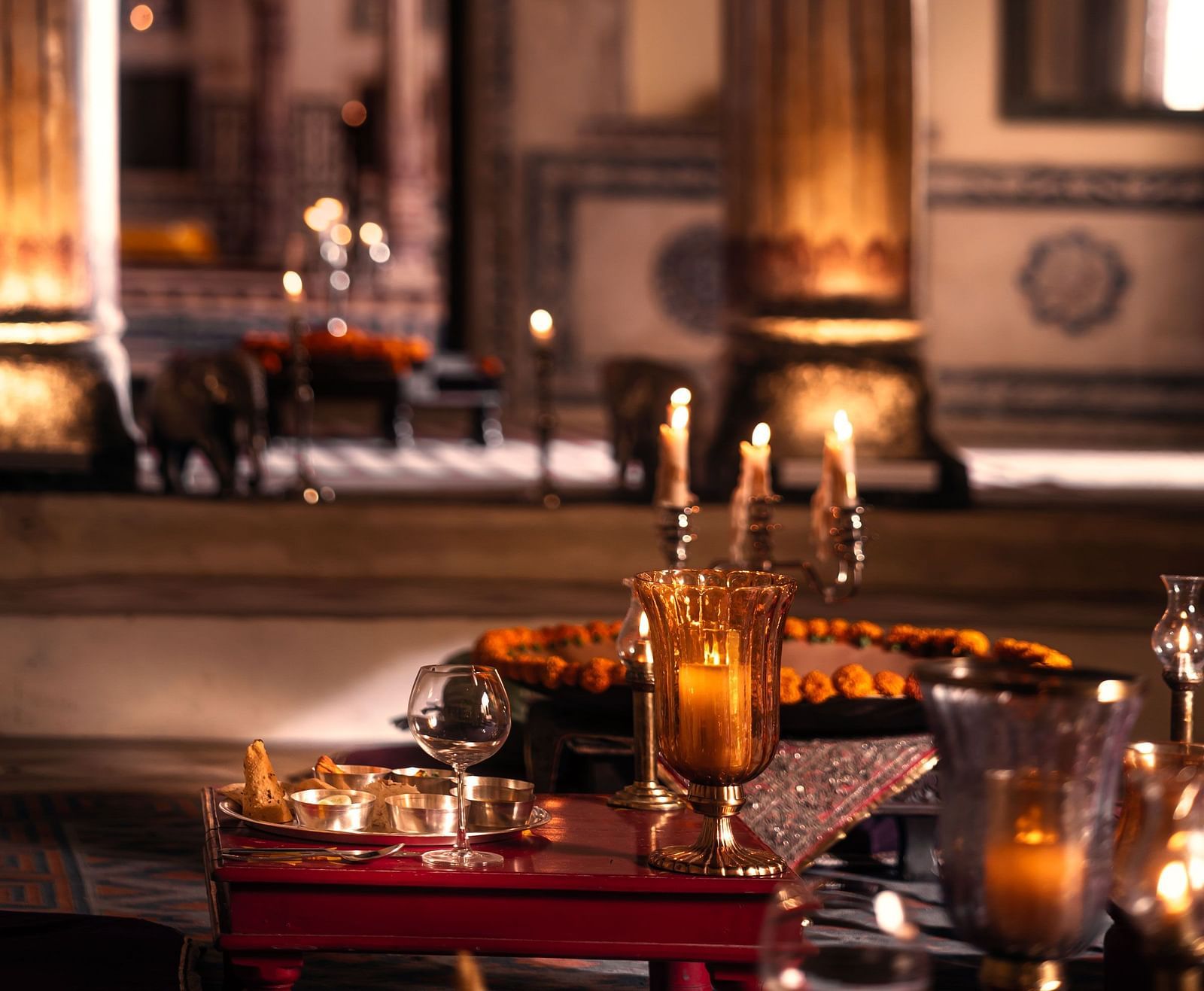 Ornate arches and warm lighting are reflected in a large mirror at Fort Barli, creating a layered and atmospheric interior view.