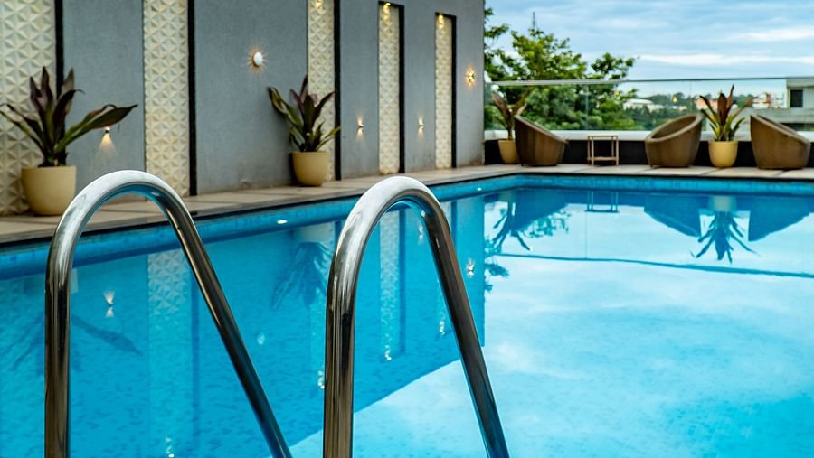 A swimming pool with lounge chairs under a bright sky.