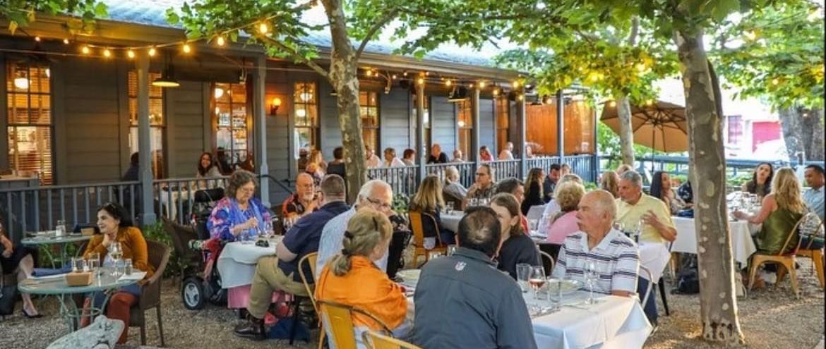 A charming al fresco dining experience awaits at the Tallman Hotel, with tables set under string lights.
