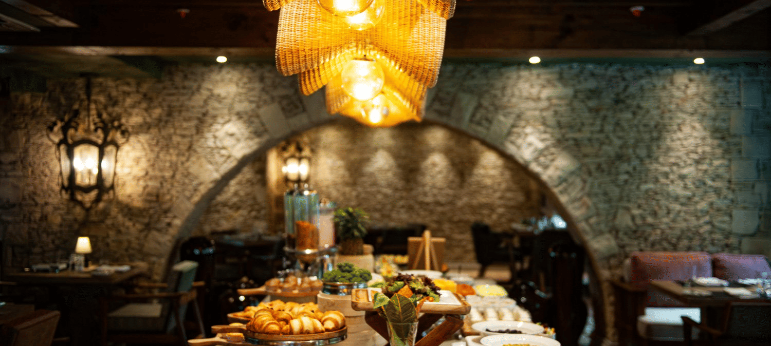 Close-up shot of the buffet table spread with well-plated dishes placed under the warm lighting from the unique chandelier at the Mila restaurant at The Evren, Vagator.