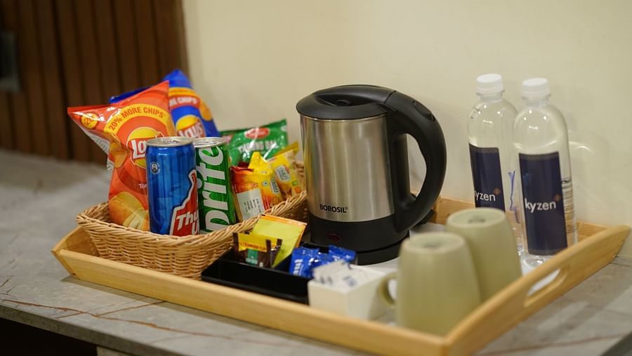 A hospitality tray with snacks, a kettle, and water bottles arranged neatly for guests at Hotel Kyzen Smartstays – Smart, Reliable, Kyzen