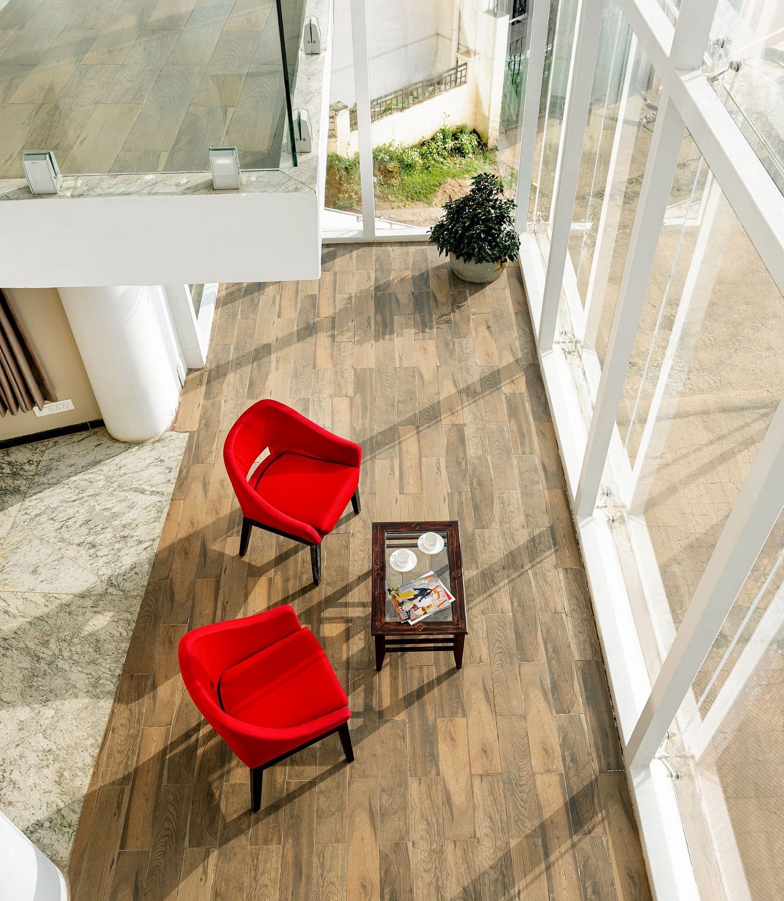 Balcony seating with two red chairs and a small table overlooking the city | Mango HIll Central, Ooty