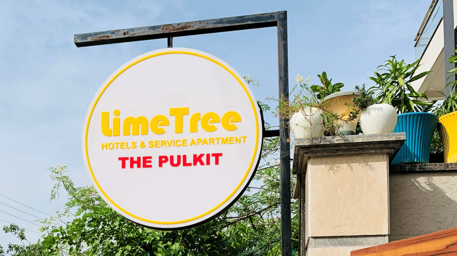 Signboard at the entrance of a property featuring surrounding greenery and a wooden panel.