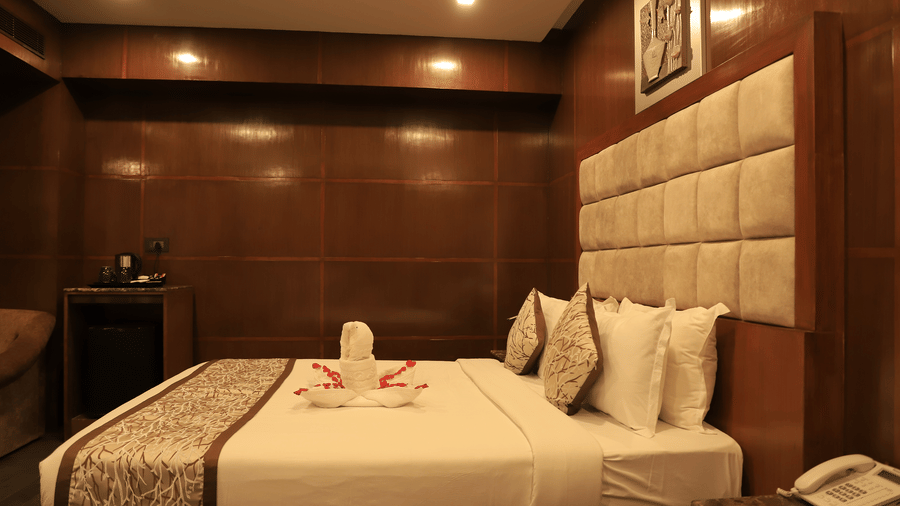 Elegant guest room with cosy interiors and wooden décor at Benzz Park, Chennai.