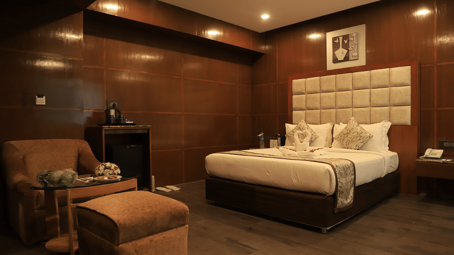 Spacious bedroom with stylish seating area and warm lighting at Benzz Park, Chennai.